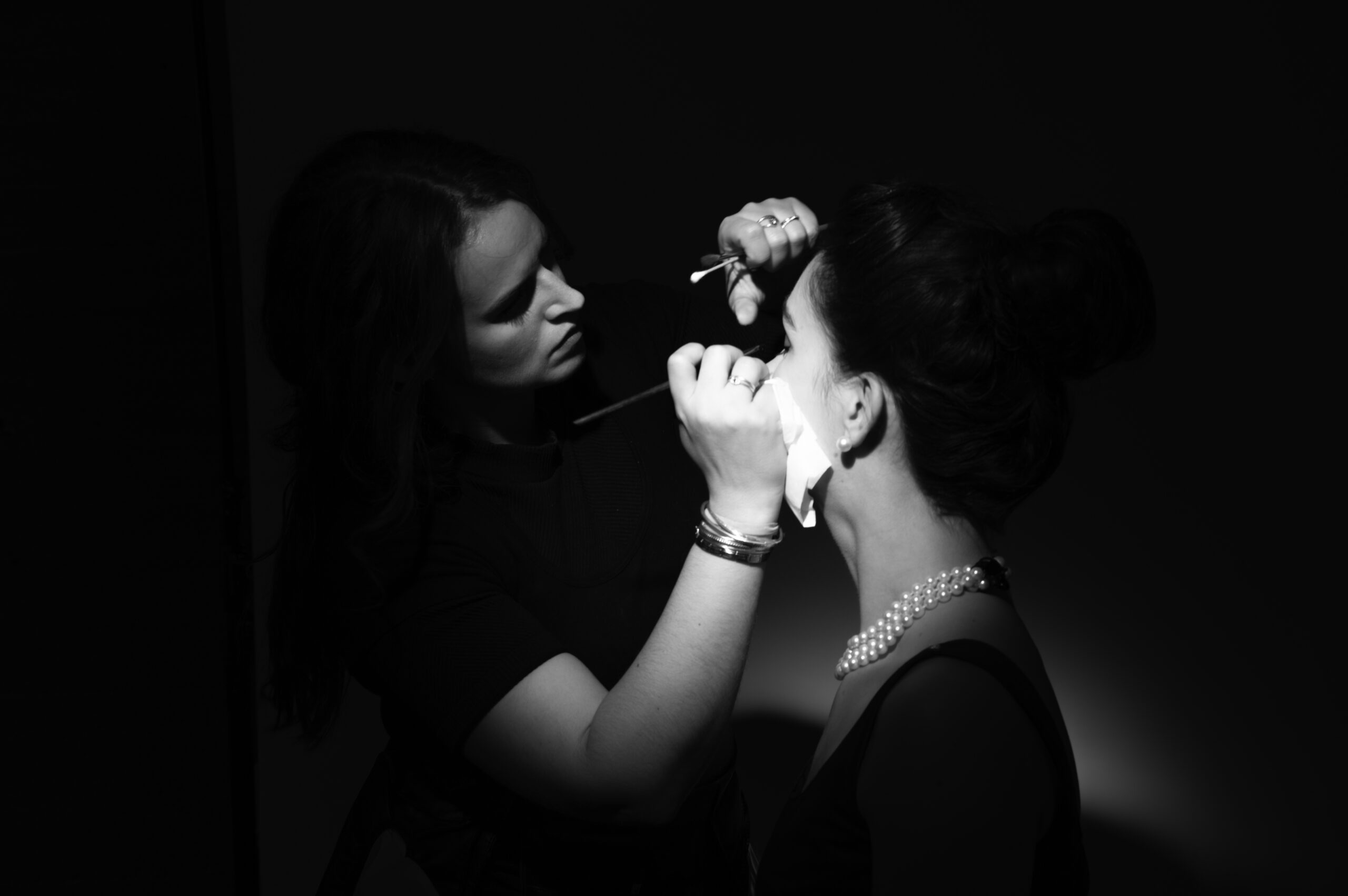 Maquilleuse professionnelle en train de retoucher une modèle